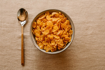 Cornflakes on a bowl on rustic background. Top view. Healthy breakfast. 	