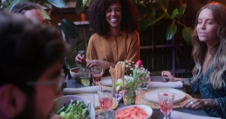 Multi-ethnic friends and couples passing food on patio meal