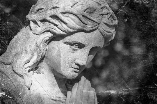 Retro styled image of Virgin Mary praying in a crown of thorns a symbol of the empathy of the suffering of Jesus Christ. Fragment of antique stone statue.