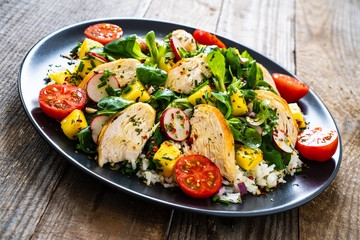 Caesar salad - fried chicken breast and vegetables on wooden table