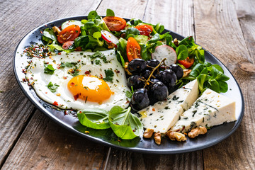 Continental breakfast - sunny side up egg, blue cheese, grapes and vegetable salad
