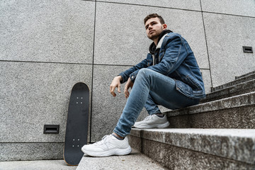 Young man sitting with skateboard on stairs