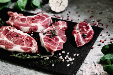 Pork neck on a black board with herbs