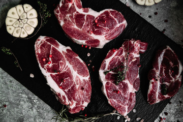 Pork neck on a black board with herbs