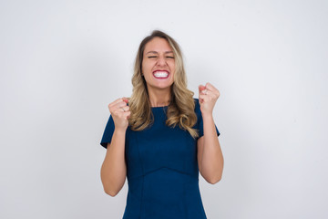 Fototapeta na wymiar Caucasian brunette woman rejoicing her success and victory clenching her fists with joy. Lucky woman being happy to achieve her aim and goals. Positive emotions, feelings.