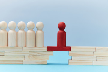 Team leadership mockup. Not like everyone. Risk. Wooden figures in line, one red person miniature ahead on bridge gap - obrazy, fototapety, plakaty