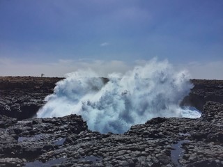 An epic ocean splash with blue sky and black rock in Buracona (Rocky lagoon) in Cabo Verde