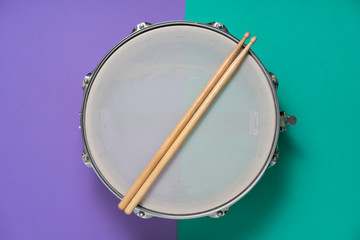 Drum stick and drum on table background, top view, music concept