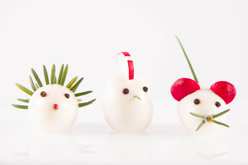 Eggs shaped like animals (with elements made of rosemary, radish, chive) on a white background