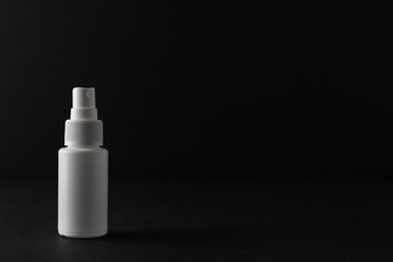 Bottle of antiseptic on black background. Antibacterial spray for hands. Plastic bottle of sanitizer with clear body.