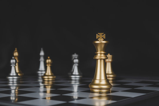 Leader. gold king with silver chess pieces on chess board game competition on dark background, business plan, chess battle, victory, success, team leader, teamwork and business strategy concept