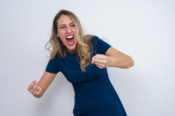 Portrait of beautiful brunette female looks with excitement at camera, keeps hands raised over head, notices something unexpected, isolated over white wall. Lovely woman reacts on sudden news.