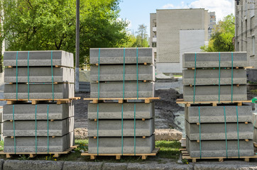 Concrete curbs on wooden pallets stand on the street during street repair
