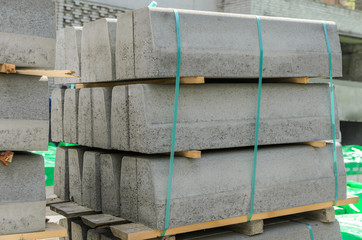 Concrete curbs on wooden pallets stand on the street during street repair