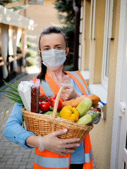 Portrait of a volunteer girl in a protective mask and medical gloves near the house of a man who is on self-isolation