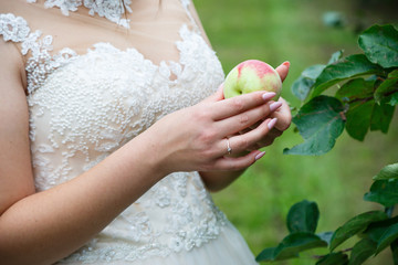 The bride holds a ripe red apple in her hands