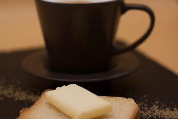 White coffee and toast with butter and sugar. Breakfast in black tray on orange background. Cappuccino.