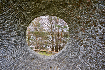 Hole in the stone with park view through it