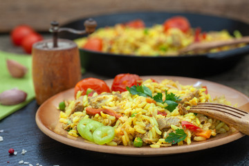Homemade pilaf with meat, rice and vegetables on a wooden table. Oriental cuisine.