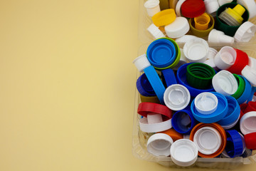 Sort plastic bottle caps. Recycling. Zero waste. Yellow background with place for text. Eco friendly. Protecting nature from pollution and debris. Sorting garbage and waste.