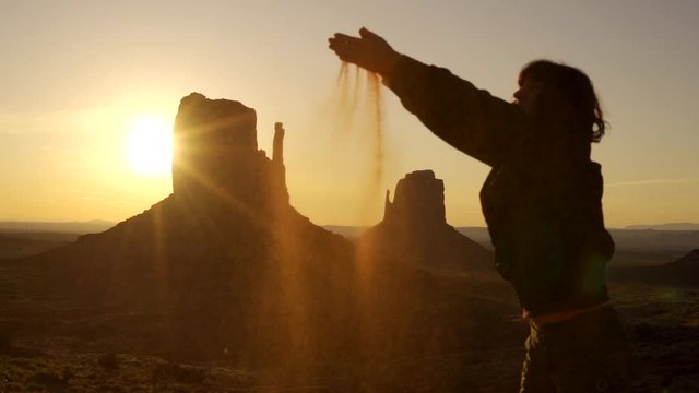 A young woman with red sand at sunrise in Monument Valley, Utah. United States