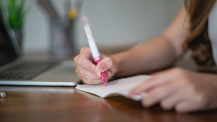 female hands with pen writing on notebook	