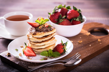 Pancakes  with chocolate sauce and fresh  strawberries on brawn wooden background. Delicious sweet dessert.