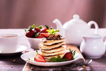 Pancakes  with chocolate sauce and fresh  strawberries on brawn wooden background. Delicious sweet dessert.