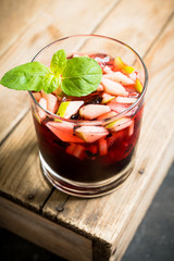 Old fashioned cocktail with blackberry liqueur and apple slices on rustic background. Selective focus. Shallow depth of field.