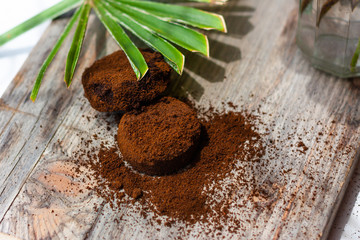 Leaves of a palm tree and coffee grounds on wooden table. Coffee grounds used as a body scrub or fertilizer for plants
