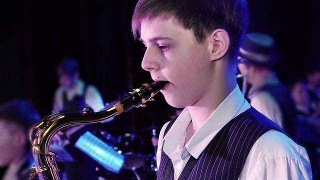 A boy plays a saxophone on stage