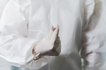 Female Nurse doctor or scientist wearing a white protective suit and gloves making the mini heart hand sign  during the coronavirus covid-19 pandemic as symbol of motivation