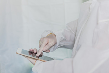 Woman Doctor or nurse wearing a protective biohazard suit and gloves using technology  analyzing data on a tablet during the rapidly spread coronavirus outbreak pandemic