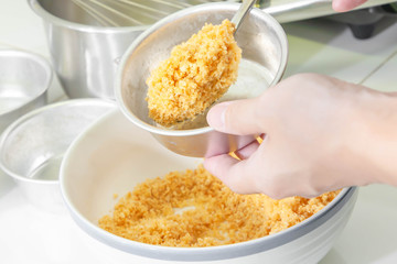 Closeup of spoon filling crispy cracker in mould pan to make base of blueberry cheesecake. Process...