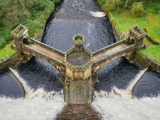 Water of the River Nidd spills over the 71m high stone dam of Scar House Reservoir in Nidderdale, Yorkshire, England, UK - the reservoir was built between 1921 and 1936.