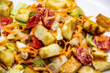 Salad with meat of pig, tomatoes, carrots, cabbage and crackers with bread runner with sauce on the white plate. Healthy and tasty meal for the diet. Delicious breakfast or lunch without GMO
