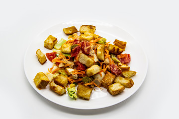 Salad with meat of pig, tomatoes, carrots, cabbage and crackers with bread runner with sauce on the white plate. Healthy and tasty meal for the diet. Delicious breakfast or lunch without GMO
