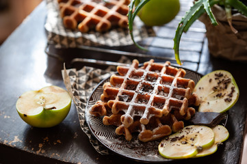 Belgian, french waffles for breakfast. Serving a dessert with chocolate, icing sugar and apples.