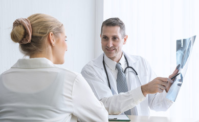 Doctor talking and diagnostic with his patient and holding x ray film in examination room at the hospital. Health concept