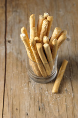 Italian bread sticks in a glass on a table with salt