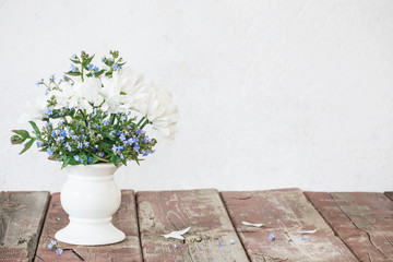 blue and white flowers in vase on old wooden table