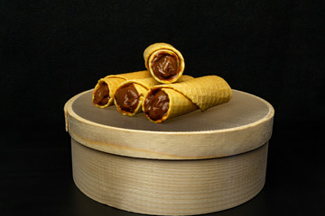 Wafer rolls with condensed milk on a white plate.