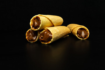 Wafer rolls with condensed milk on a white plate.