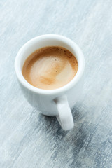 Cup of coffee on bright wooden background.