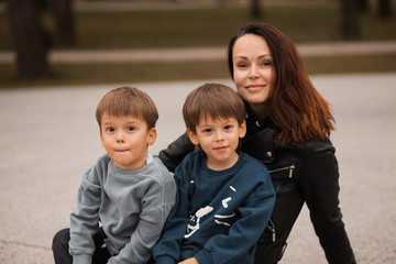 Happy american brunette mother with two cute twin brothers smiling