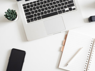 top view of office desk table with notebook, laptop, plastic plant, smartphone on white background, graphic designer, Creative Designer concept.
