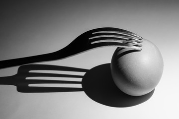 Fork and eggs and their shadow, close-up on a white background