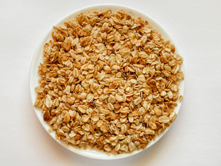 On white isolated background granola on plate, breakfast dish, snack. On the photo is a granule of...