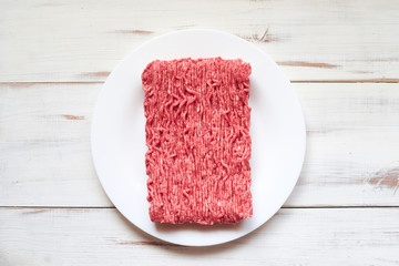 Raw minced meat on a wooden background.