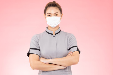 Attractive Beautiful Asian woman maid wearing face mask smile and cross arm feeling so happiness and confident,Isolated on pink background,Cleaning Service concept